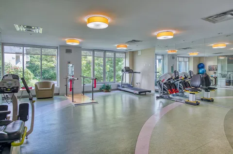 Fitness room with exercise equipment beside large windows