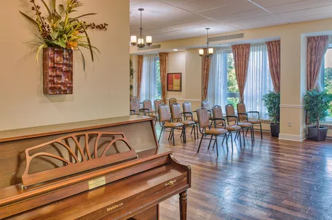 Activity room with a piano and chairs beside large windows