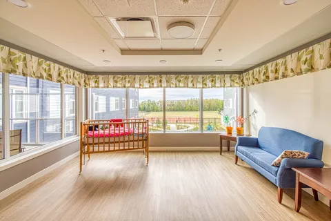 Bright corner room with a blue sofa, a wooden crib and broad windows