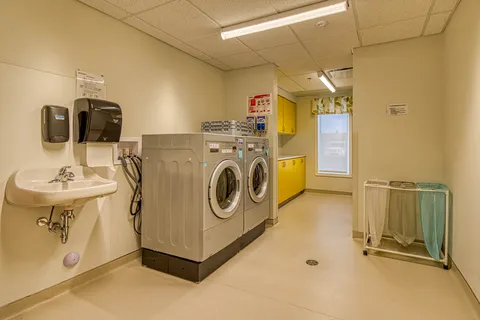 Laundry room with a sink, two washing machines and yellow cabinets
