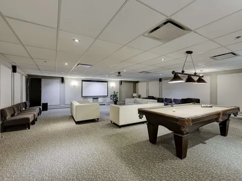 Games room with a pool table, sofas and a blank projection screen