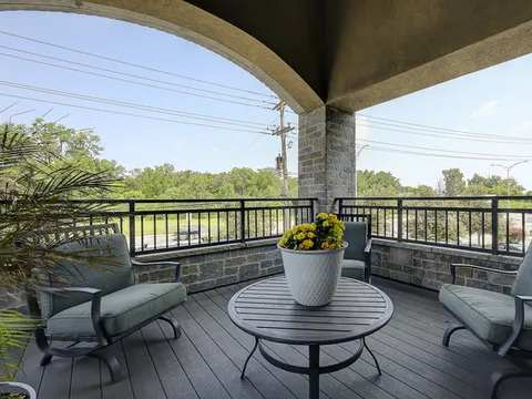 Covered balcony with cushioned chairs and a round table with flowers