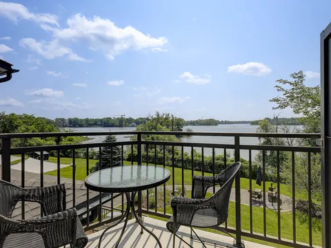 Balcony with a glass table and wicker chairs overlooking trees and water
