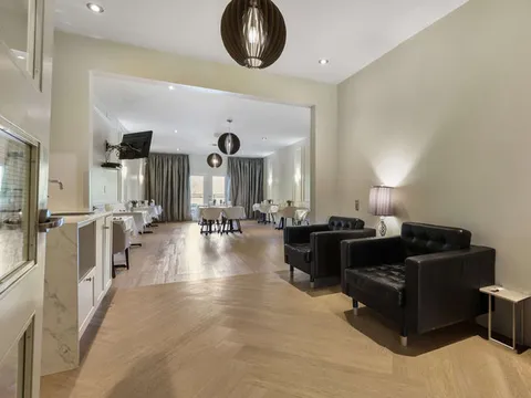 Room with leather armchairs and tables beyond an open doorway