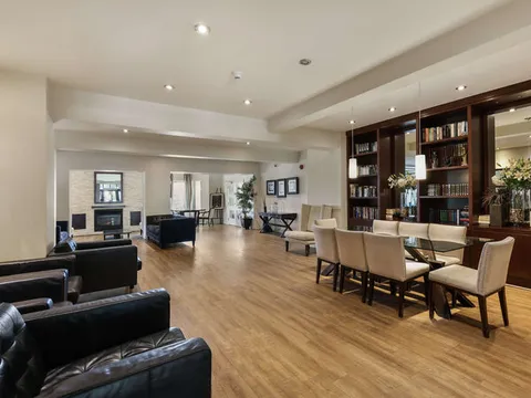 Room with leather armchairs, a table, bookshelves and a fireplace