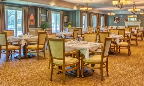 Dining room with set tables, wooden chairs and large windows.