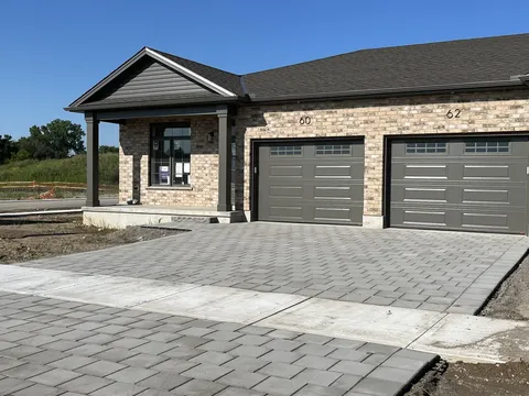 Attached brick homes with garage doors and a paved driveway