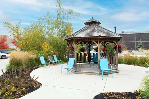 Wooden gazebo surrounded by turquoise chairs, grasses and flower baskets