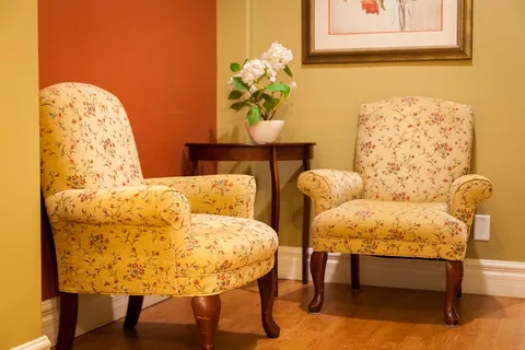 Two patterned armchairs beside a small table and flowers.