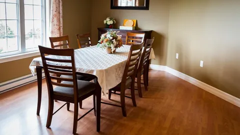 Small dining table and wooden chairs beside a window.