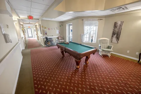 Green pool table beside an armchair, a wheelchair and windows