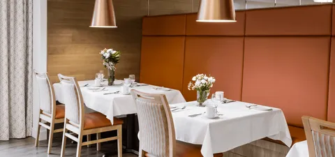Set dining tables beside an orange upholstered bench
