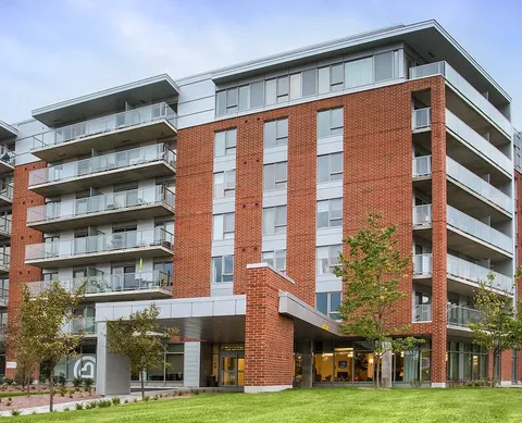 Brick residence with glass balconies, a covered entrance and a lawn
