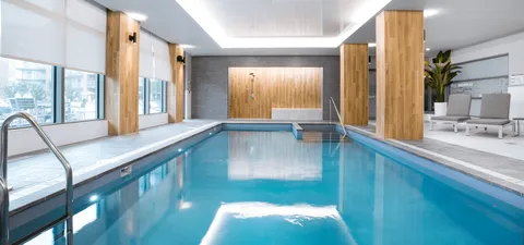Indoor swimming pool with handrails, wood columns and poolside chairs