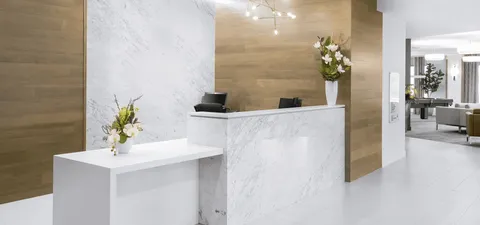 Reception desk with a white marble finish, flowers and wood panelling