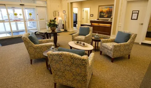 Room with upholstered armchairs, a coffee table and upright piano