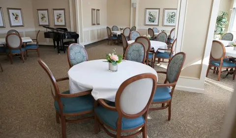Dining tables and upholstered chairs beside windows and botanical wall art