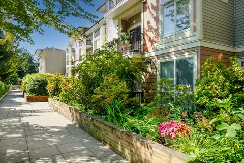 Residence balconies beside a walkway and raised flower beds