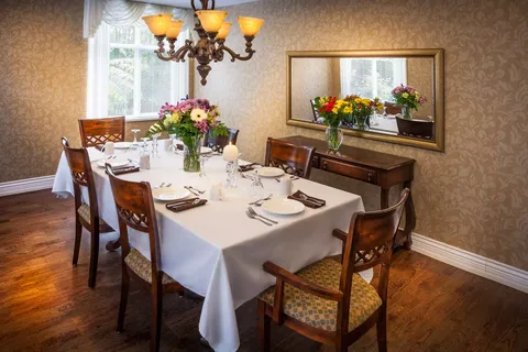Dining table with white place settings, flowers and a wall mirror