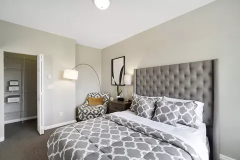 Bedroom with a tufted headboard, patterned bedding and bedside lamps