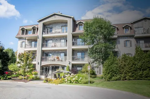 Stone-fronted residence with balconies, lawns, shrubs and an outdoor swing