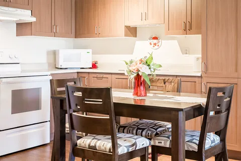 Kitchen with wood cabinets, white appliances and a four-chair dining table