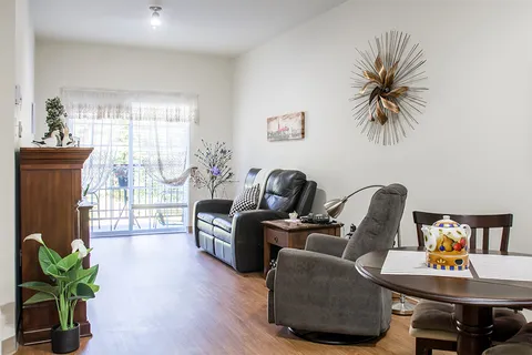 Sitting area with a sofa, recliner, dining table and sliding door to a balcony