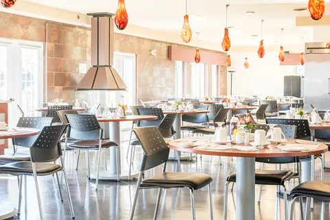 Dining room with round set tables, black chairs and orange pendant lights