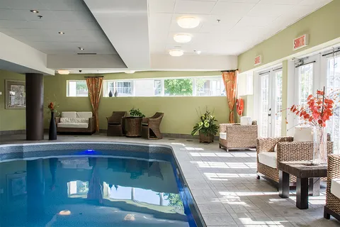 Indoor swimming pool with wicker seating, tiled surround and large windows