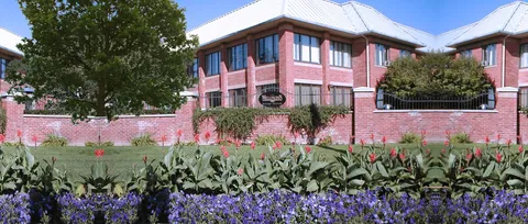 Brick residence behind landscaped flower beds and a low wall