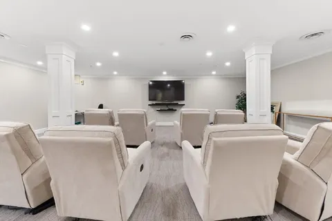 Theatre with upholstered seating and a wall-mounted screen.