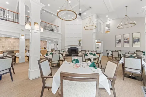 Dining room with set tables, chairs and tall windows.