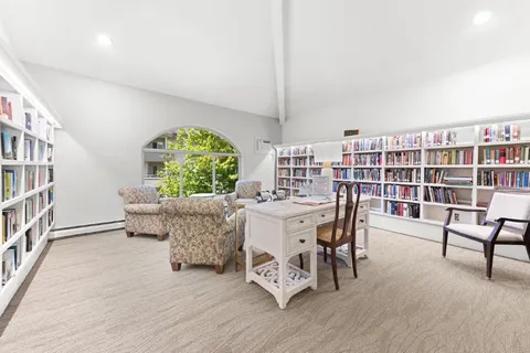 Library with bookcases, a desk and upholstered seating.