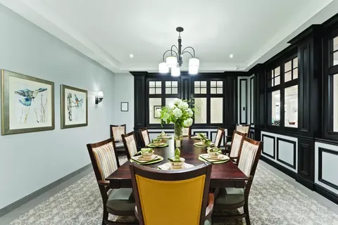 Room with a long dining table, chairs and framed bird artwork