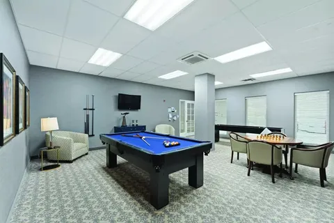 Room with a pool table, armchairs and a television