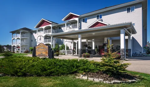 Chateau Three Hills building with balconies, a covered entrance and landscaped beds.