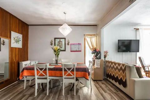 Open dining and sitting room with table, chairs and television.