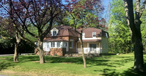 Two-storey house with front lawn and mature trees.