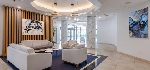Lobby with pale armchairs, a coffee table, patterned rug and abstract wall art