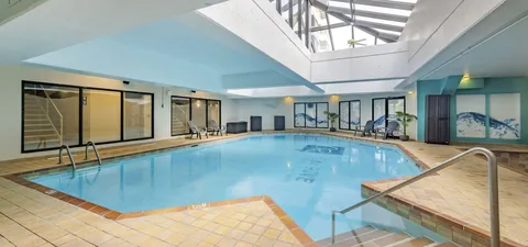 Indoor pool with railings, lounge chairs and windows