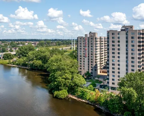Aerial view of a tall residence beside a river, trees and roads