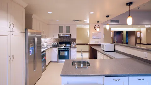 Kitchen with white cabinets, a refrigerator, range and counter with a sink