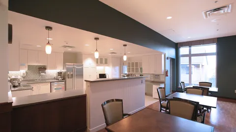 Tables and chairs beside an open kitchen with white cabinets