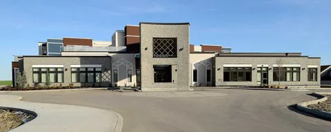 Residence exterior with stone and metal cladding, large windows and a curved driveway