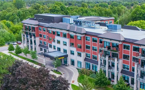 Aerial view of a residence with balconies, a covered entrance and trees