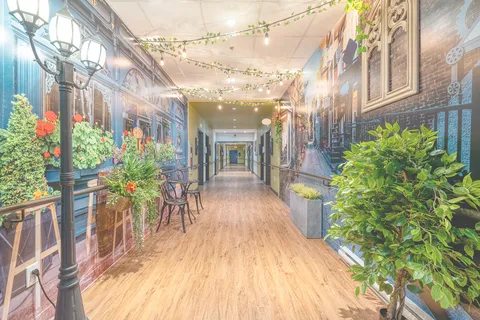 Hallway with village murals, decorative street lamps and potted plants