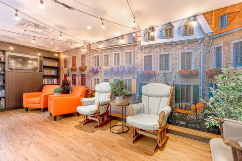 Orange and white armchairs beside a wall mural of village buildings