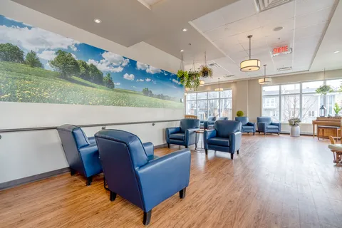 Blue armchairs beside large windows and a landscape mural