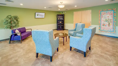 Seating room with blue armchairs, a coffee table and a bookcase.