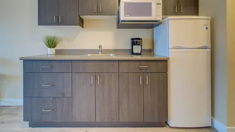 Kitchenette with a refrigerator, microwave, sink and cabinets.